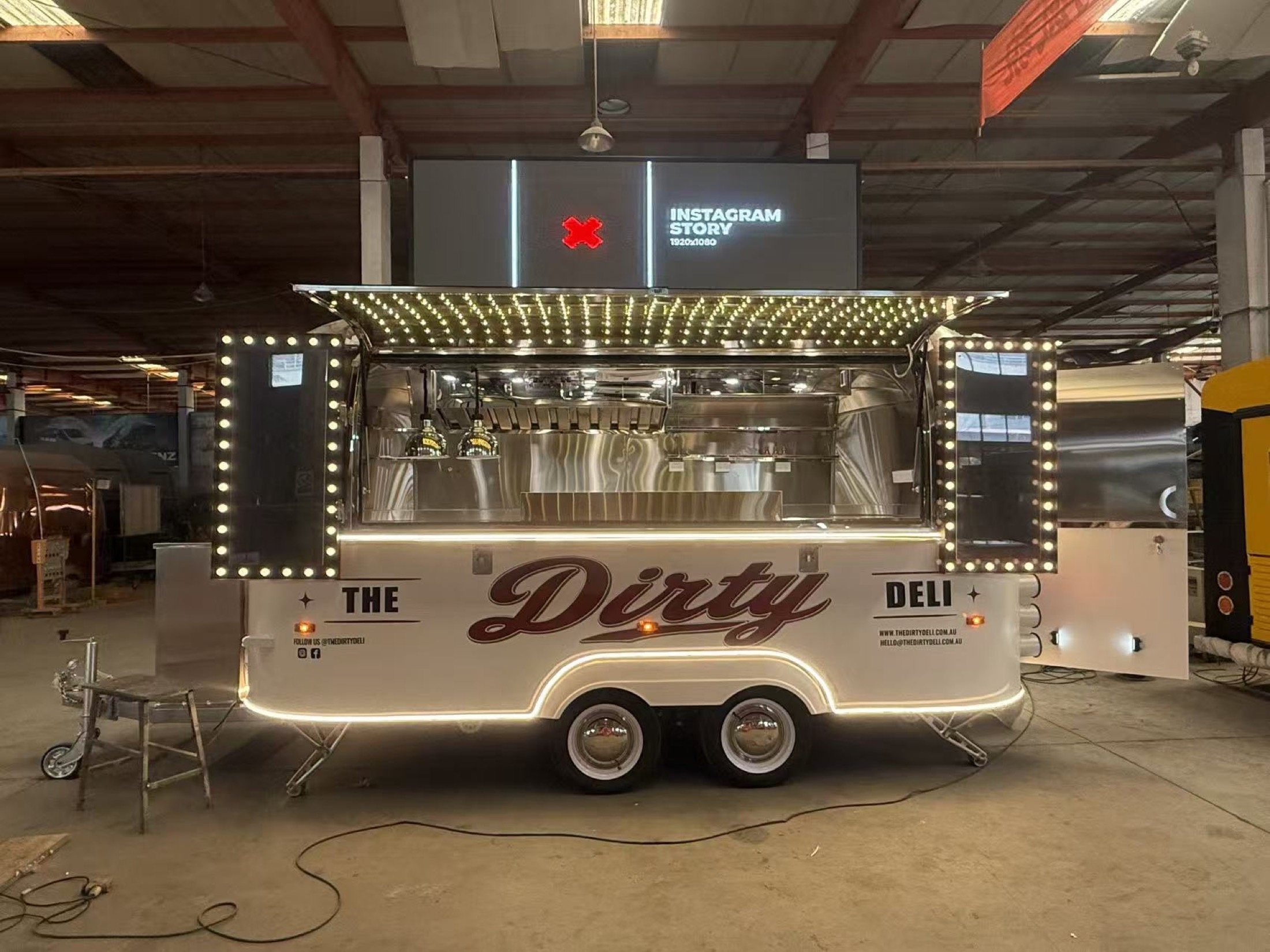 The Dirty Deli trailer with its serving hatch open and marquee lights illuminated