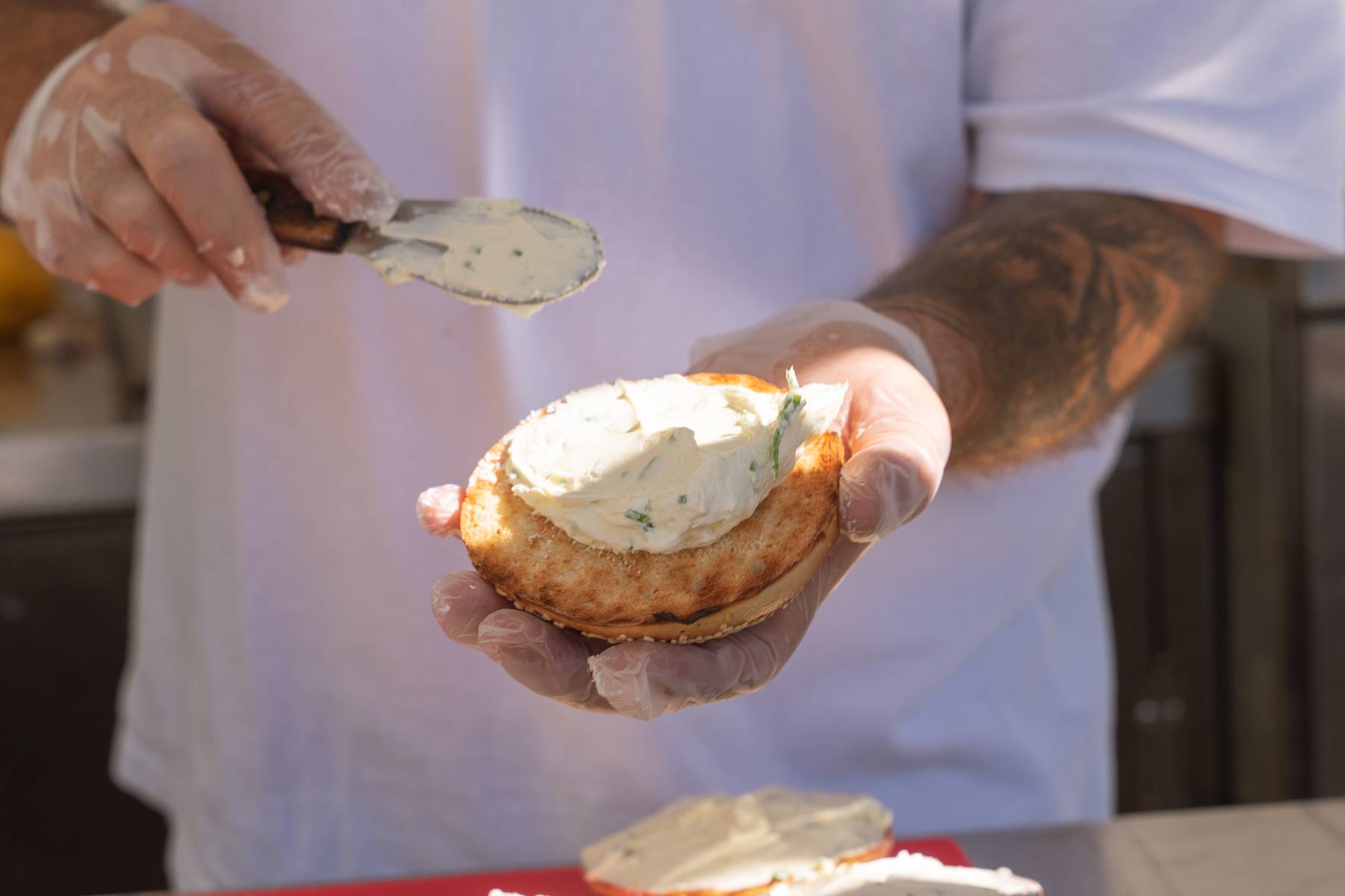Cream cheese being spread on a toasted bagel