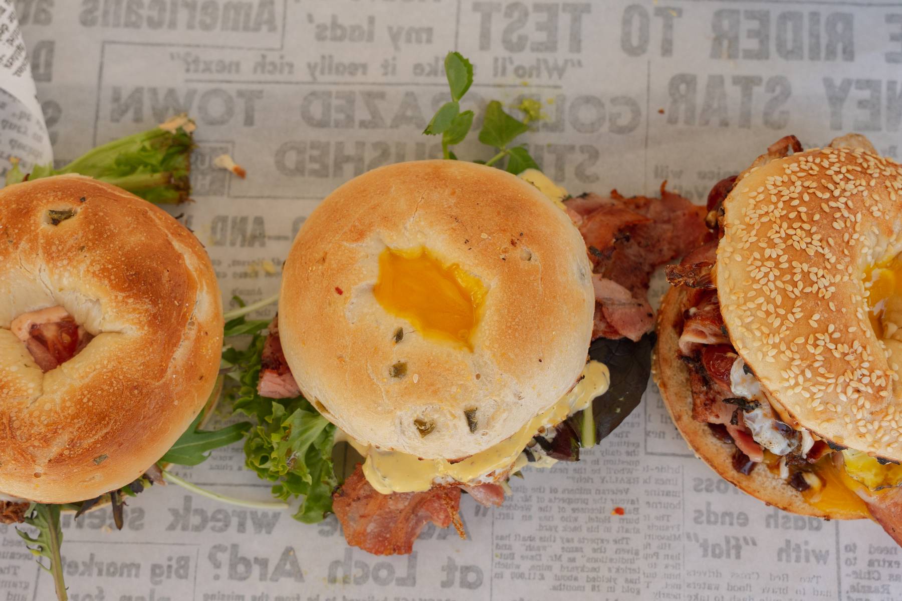 Three filled bagels on deli paper