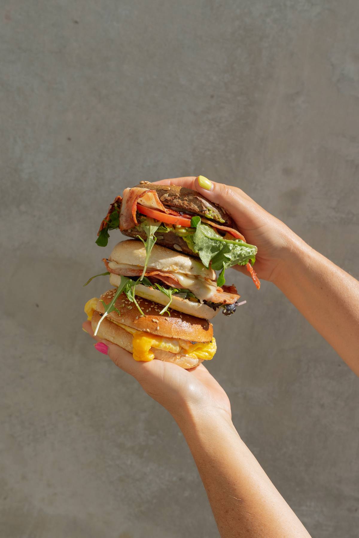 A stack of different filled bagels held in hand